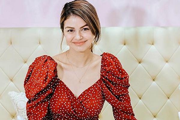 Janine Gutierrez is smiling while wearing red, polka dot long sleeve blouse.