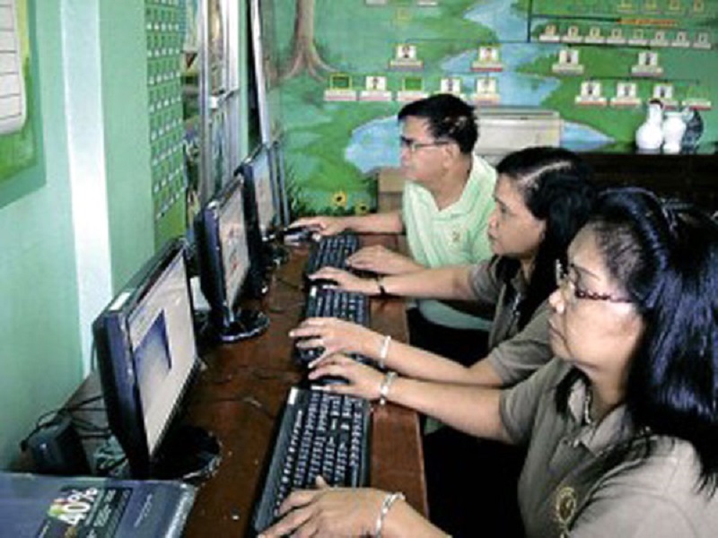 Tatlong guro ang gumagamit ng computer para sa paghahanda ng kanilang klase.