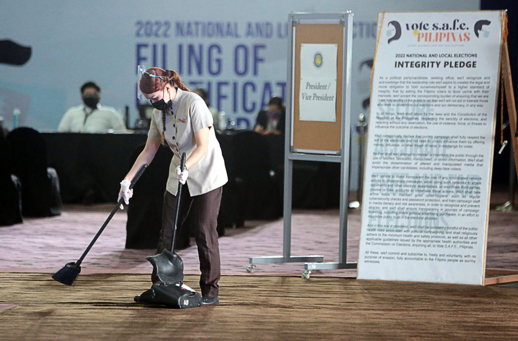 A worker sweeps the floor of the venue set up by the Comelec at Sofitel hotel in Pasay City for filing certificates of candidacy for the May 2022 polls, where politicians of every stripe have strode in and out since Oct. 1, with more expected till Friday. At right is the “integrity pledge” that is always worth remembering in times like these.